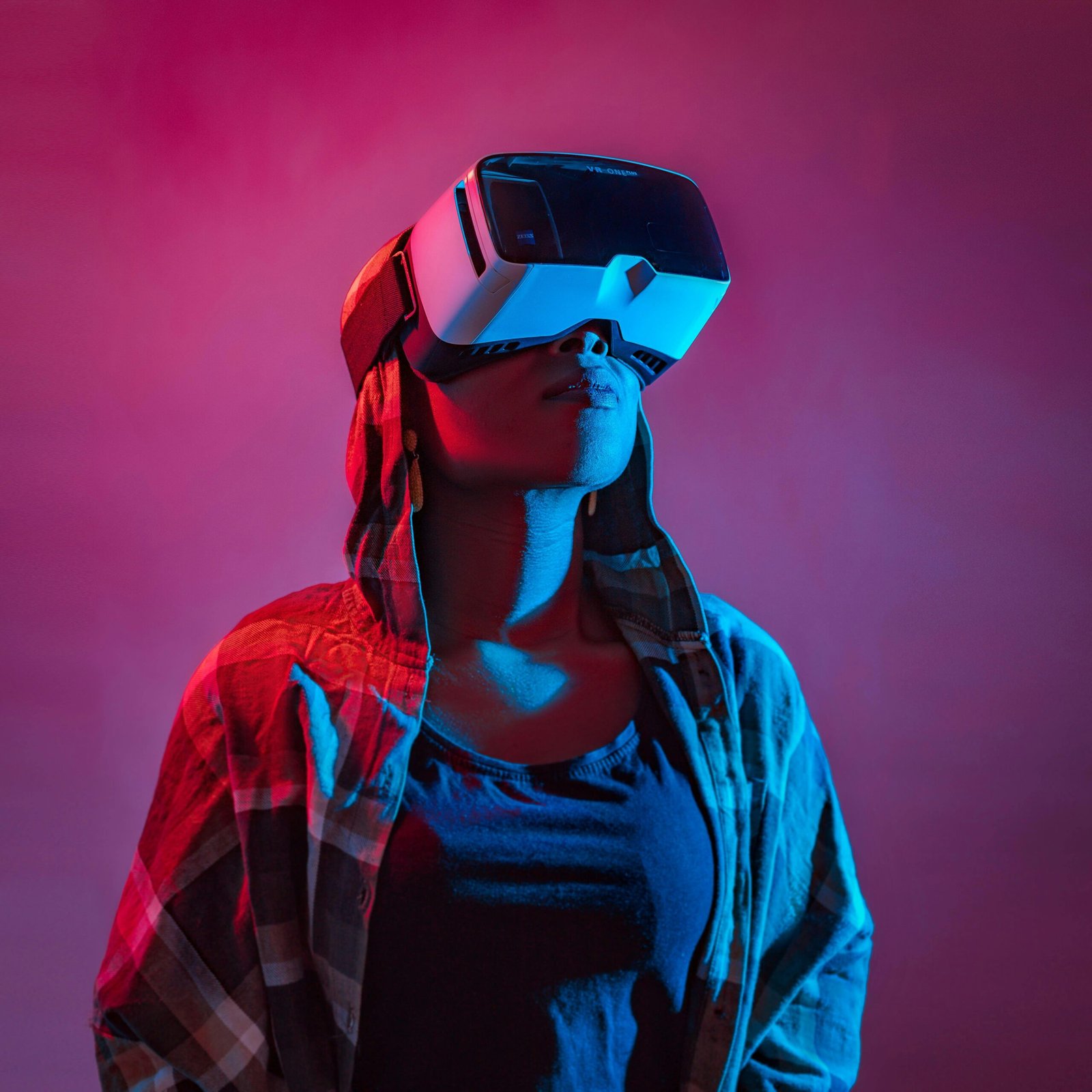 Woman immersed in virtual reality with VR headset in vibrant lighting.